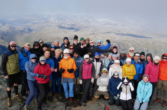 En gruppe mennesker som poserer for et bilde på et fjell