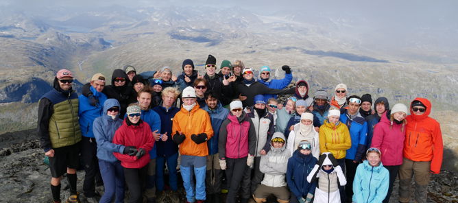 En gruppe mennesker som poserer for et bilde på et fjell En gruppe mennesker som poserer for et bilde på et fjell